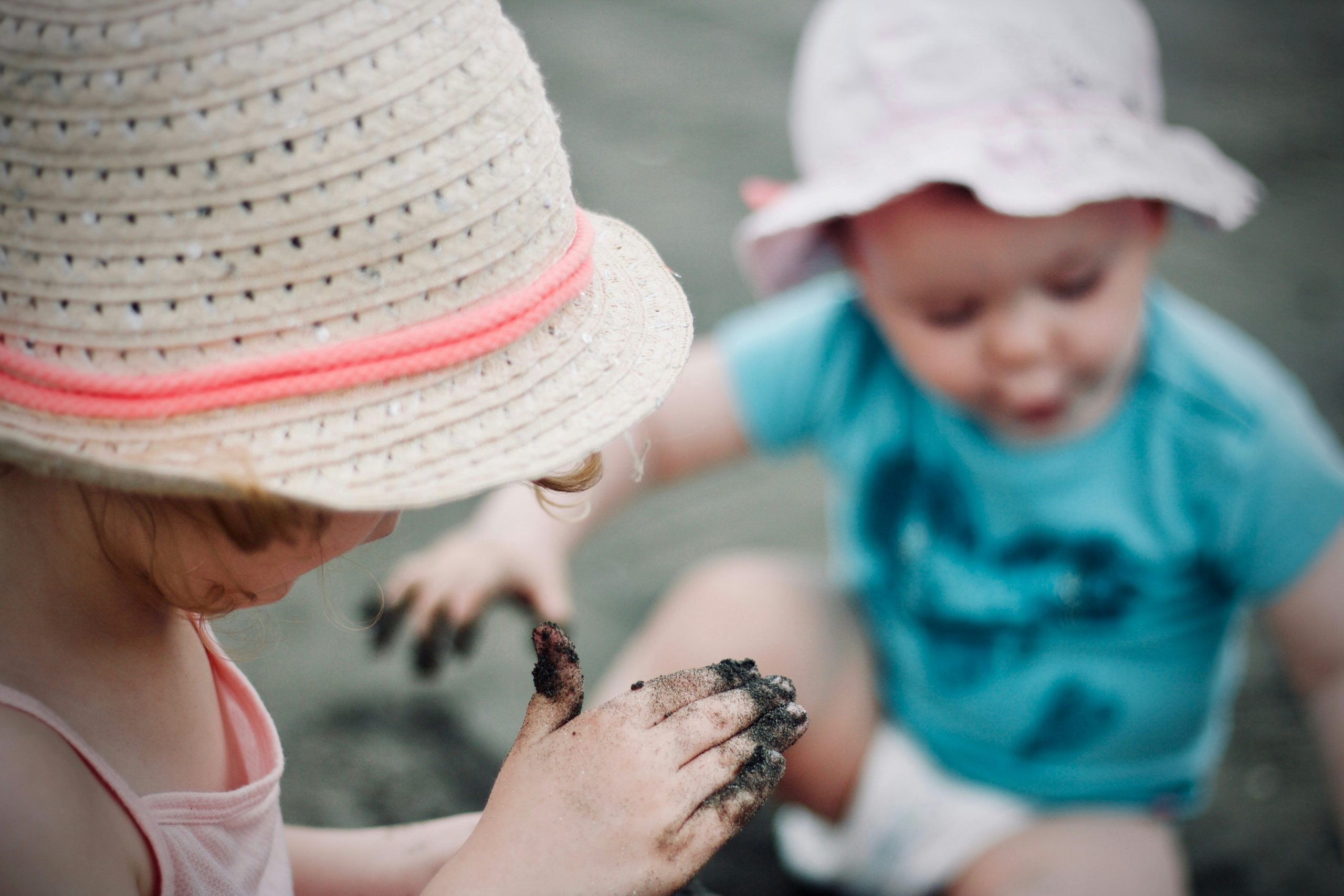 Two small children playing with mud in their hands