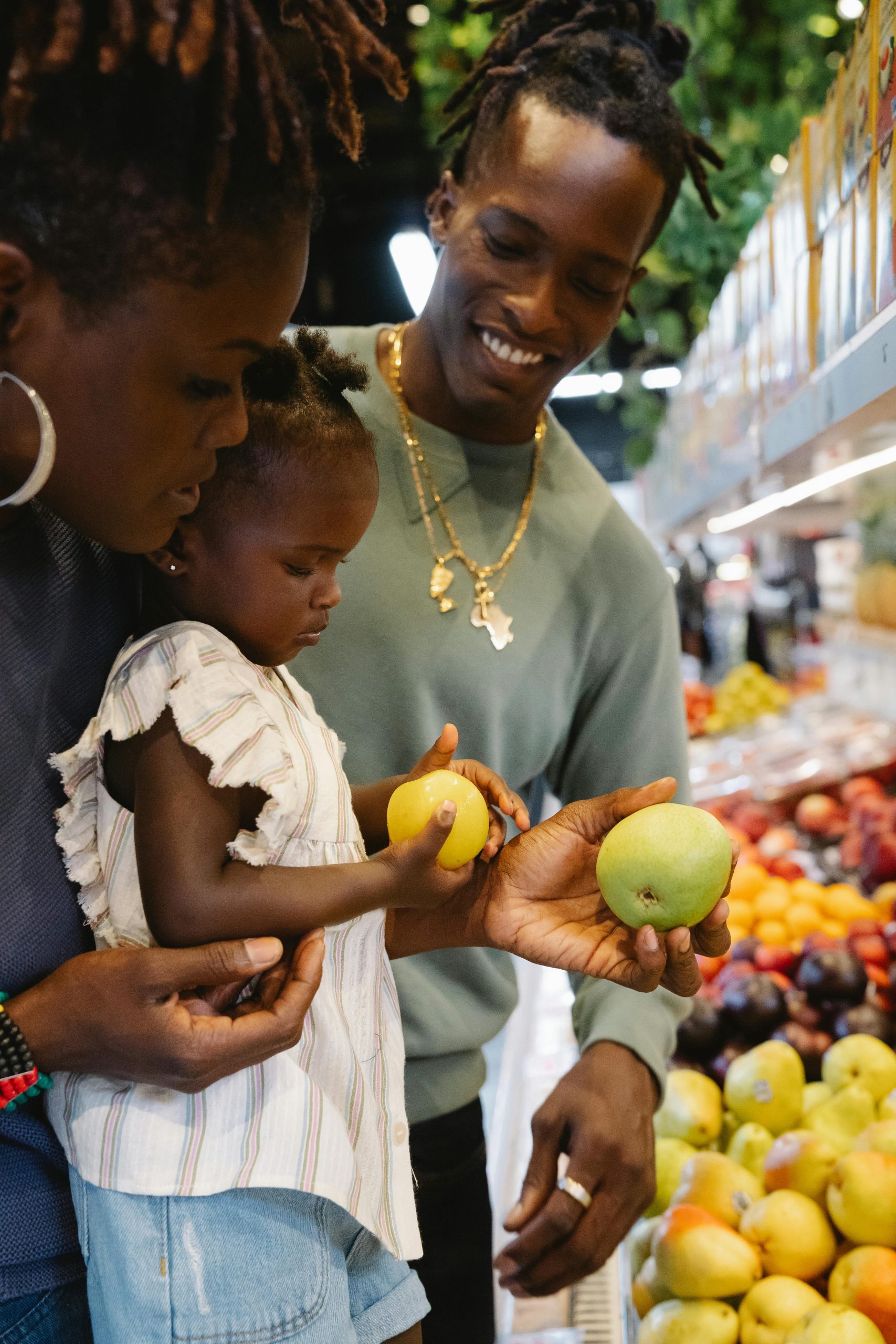 Parents and child picking up produce at grocery store